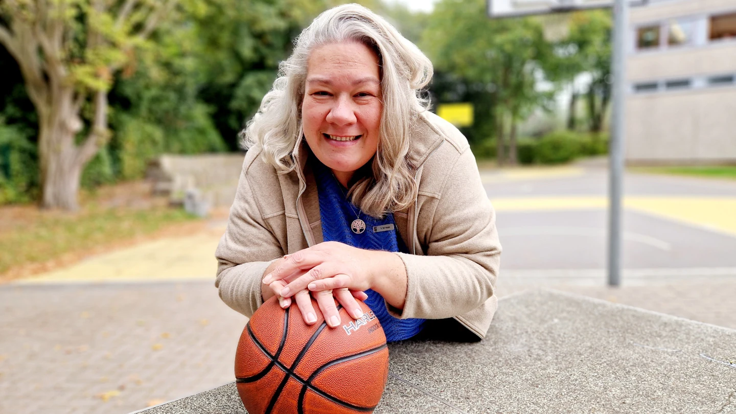 Originalfoto: Anita Herrmann, Kreisbehindertenbeauftragte der Wesermarsch, mit Basketball auf einem Schulhof
