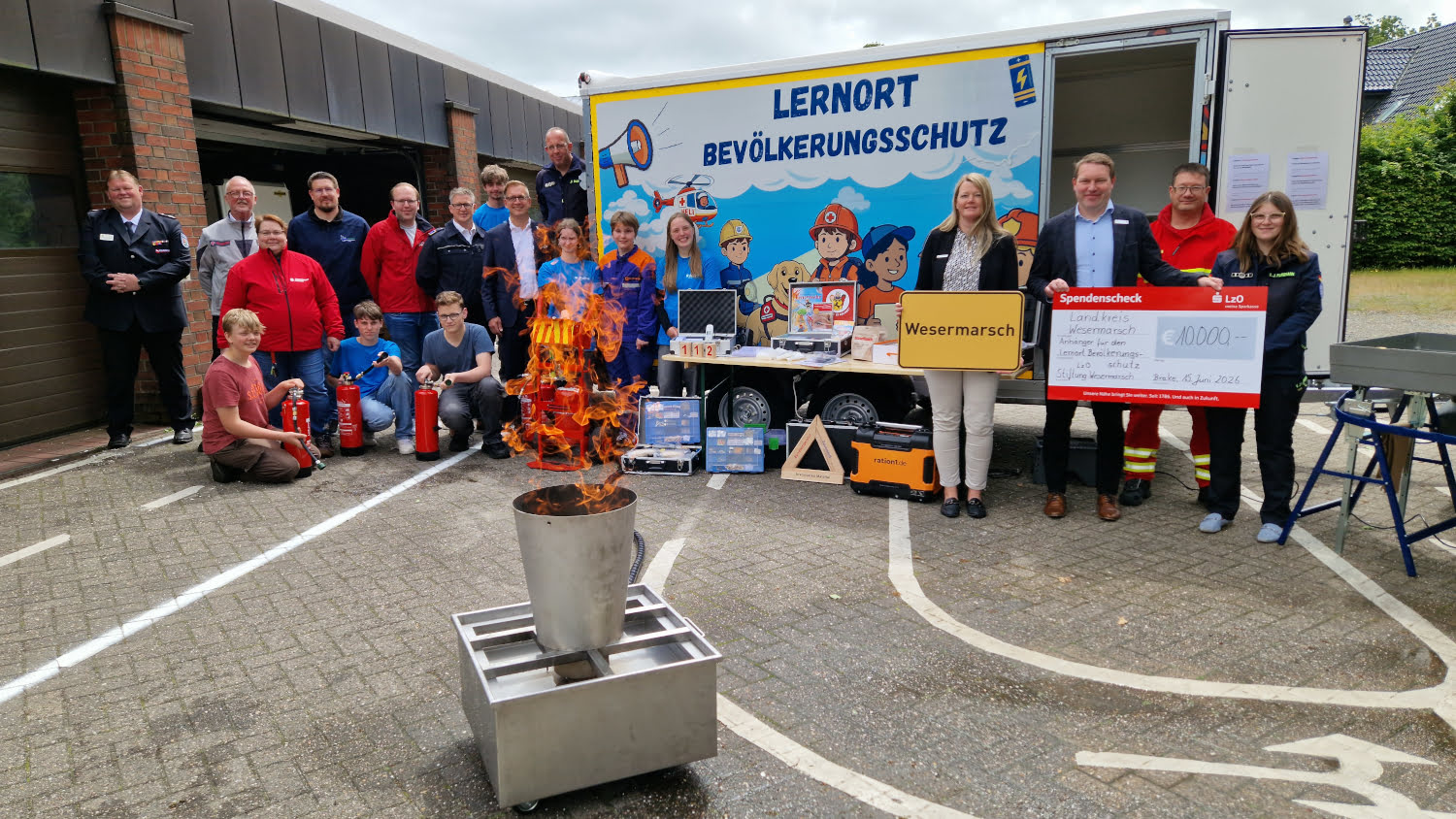 Kreisrätin Maren Würger, Landrat Stephan Siefken, LzO-Stiftungsratsmitglied Jan Kurka sowie Hilfs- und Rettungsorganisationen am mobilen Lernort Bevölkerungsschutz in Brake